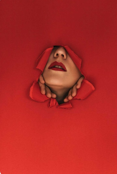 Rosto feminino com maquilhagem vermelha saindo de papel vermelho rasgado