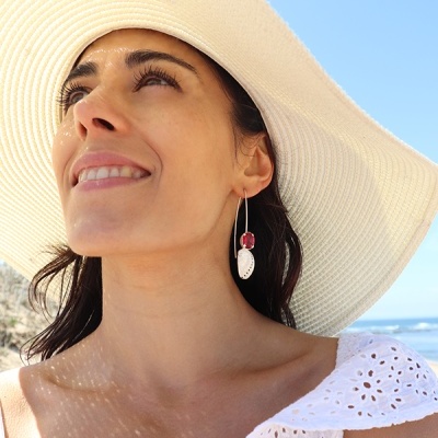 Mulher com brincos pendurados, chapéu branco de aba larga e vestido branco rendado