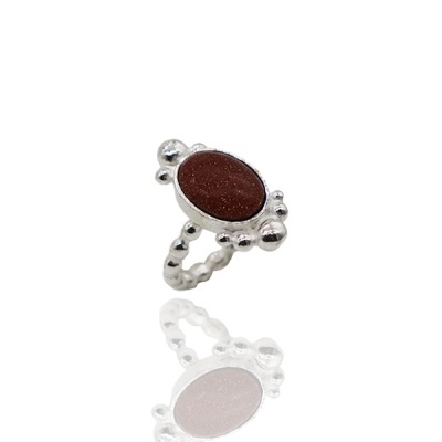 Anel prateado com pedra oval castanha e detalhes esféricos