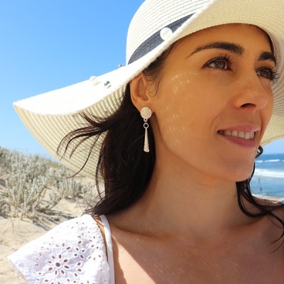 Mulher usando chapéu de palha branco largo e vestido branco na praia