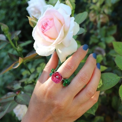 Mão com anel floral segurando rosa branca e rosa pálido ao ar livre