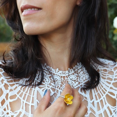 Mulher com anel de flor amarela e vestido branco rendado