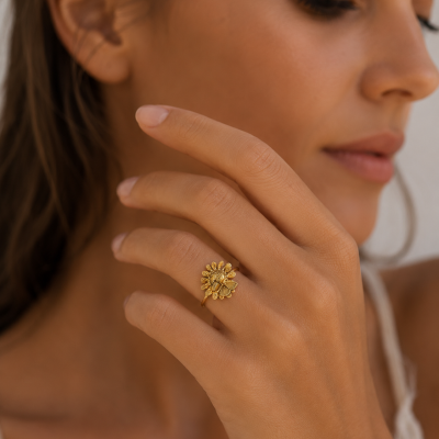 Anel dourado em forma de flor usando numa mão feminina