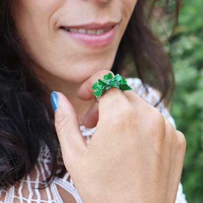 Anel verde com elementos em forma de folhas numa mão feminina