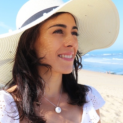 Mulher na praia com chapéu de aba larga branco e vestido branco