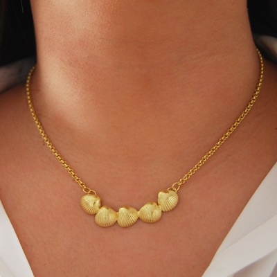 Colar dourado com pendentes de conchas no pescoço