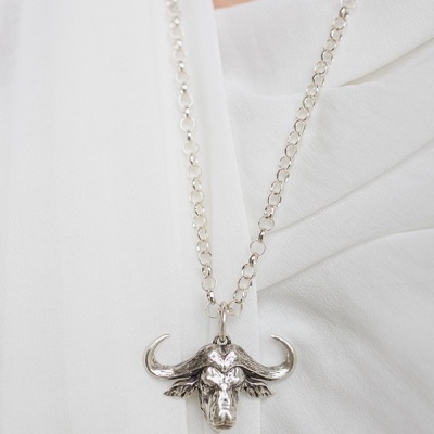 Colar com pendente cabeça de touro em metal prateado sobre tecido branco