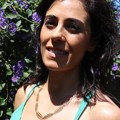 Colar dourado com elos de folha num pescoço feminino