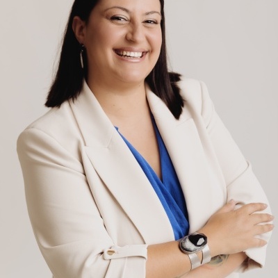 Mulher com blazer branco e camisa azul usando relógio de bracelete metálica prateada