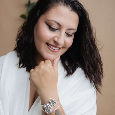 Bracelete prateado com cabeça de rinoceronte no braço de mulher com tatuagem