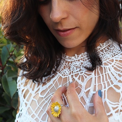 Mulher com blusa branca de crochê e anel de girassol amarelo