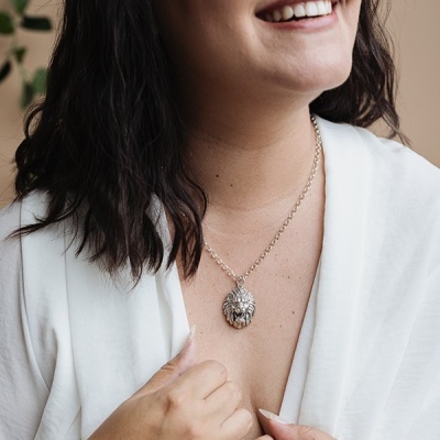 Colar com pendente cabeça de leão prateado em mulher de camisa branca