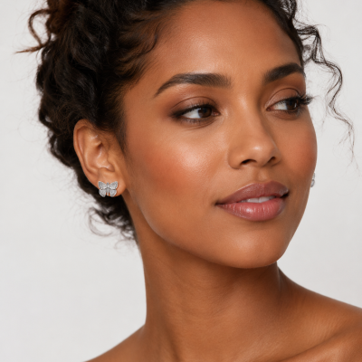 Brincos prateados em forma de borboleta numa mulher com pele morena e cabelo encaracolado
