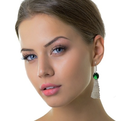 Brincos pendentes com cristal verde e pendente branco em mulher com cabelo castanho e olhos azuis
