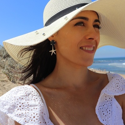 Mulher na praia com chapéu de palha branco e vestido branco