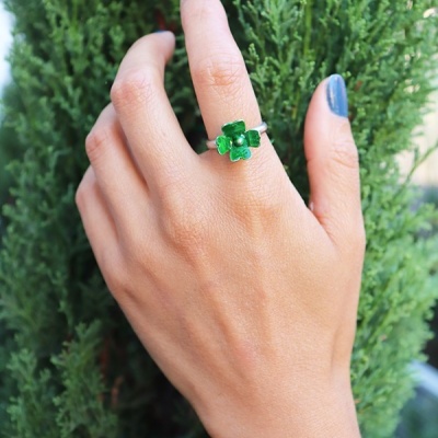 Mão com anel de flor verde em fundo de folhagem