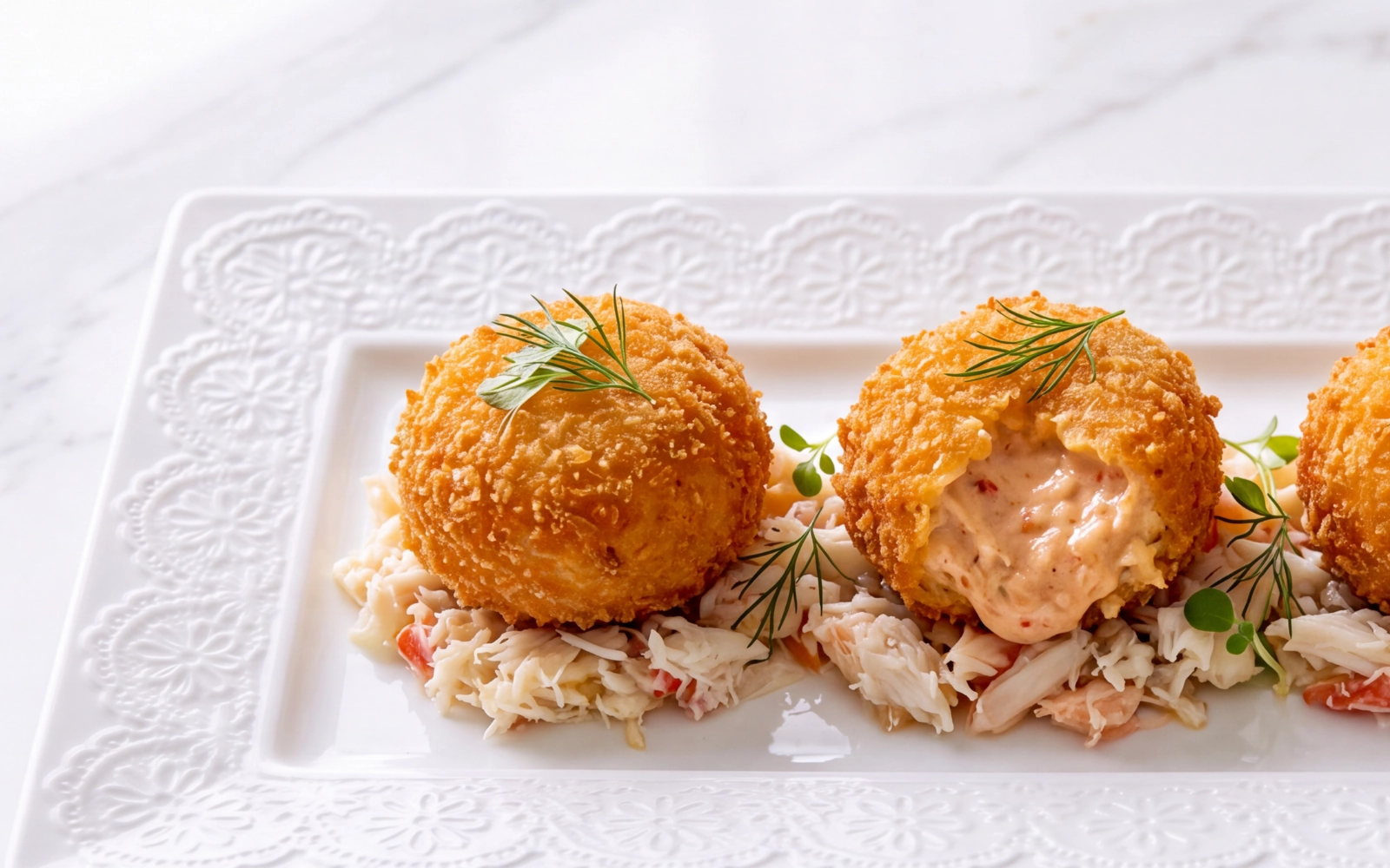 Carne Branca de Santola bolinhos fritos crocantes recheados com creme sobre salada de marisco em prato branco decorativo