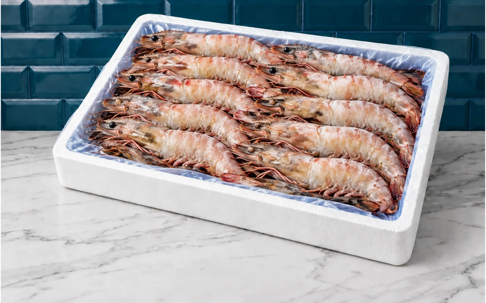 Camarão Selvagem de Moçambique Caixa de isopor com camarões congelados sobre bancada de mármore e azulejos azuis