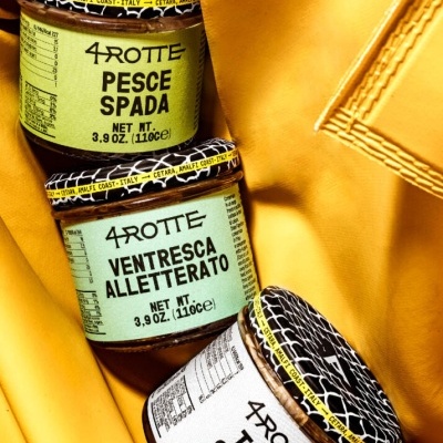 Três frascos de alimentos 4 ROTTE com etiquetas coloridas e tampa preta sobre tecido amarelo.
