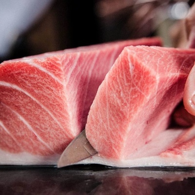 Fatia de peixe cru cor-de-rosa a ser cortada por uma faca