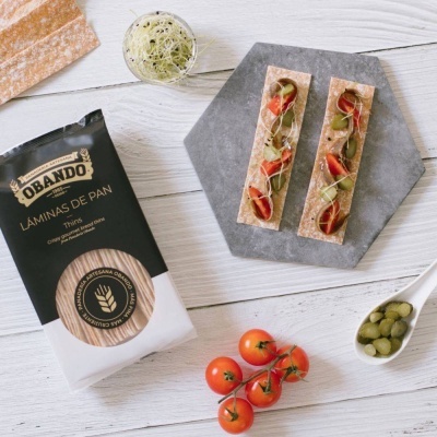 Pacote de lâminas de pão Obando, lâminas de pão com tomate e picles, tomate-cereja e picles em colher numa mesa de madeira