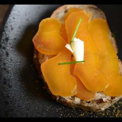 Tosta de pão com ovas laranja, manteiga e cebolinho num prato preto