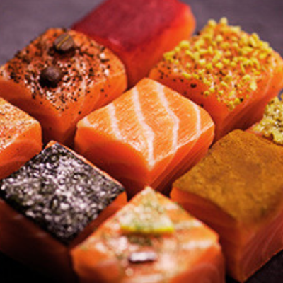 Cubos de salmão com diversas coberturas em superfície escura