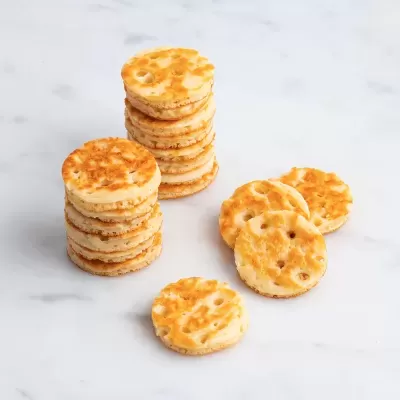 Bolachas redondas douradas empilhadas e soltas sobre superfície branca