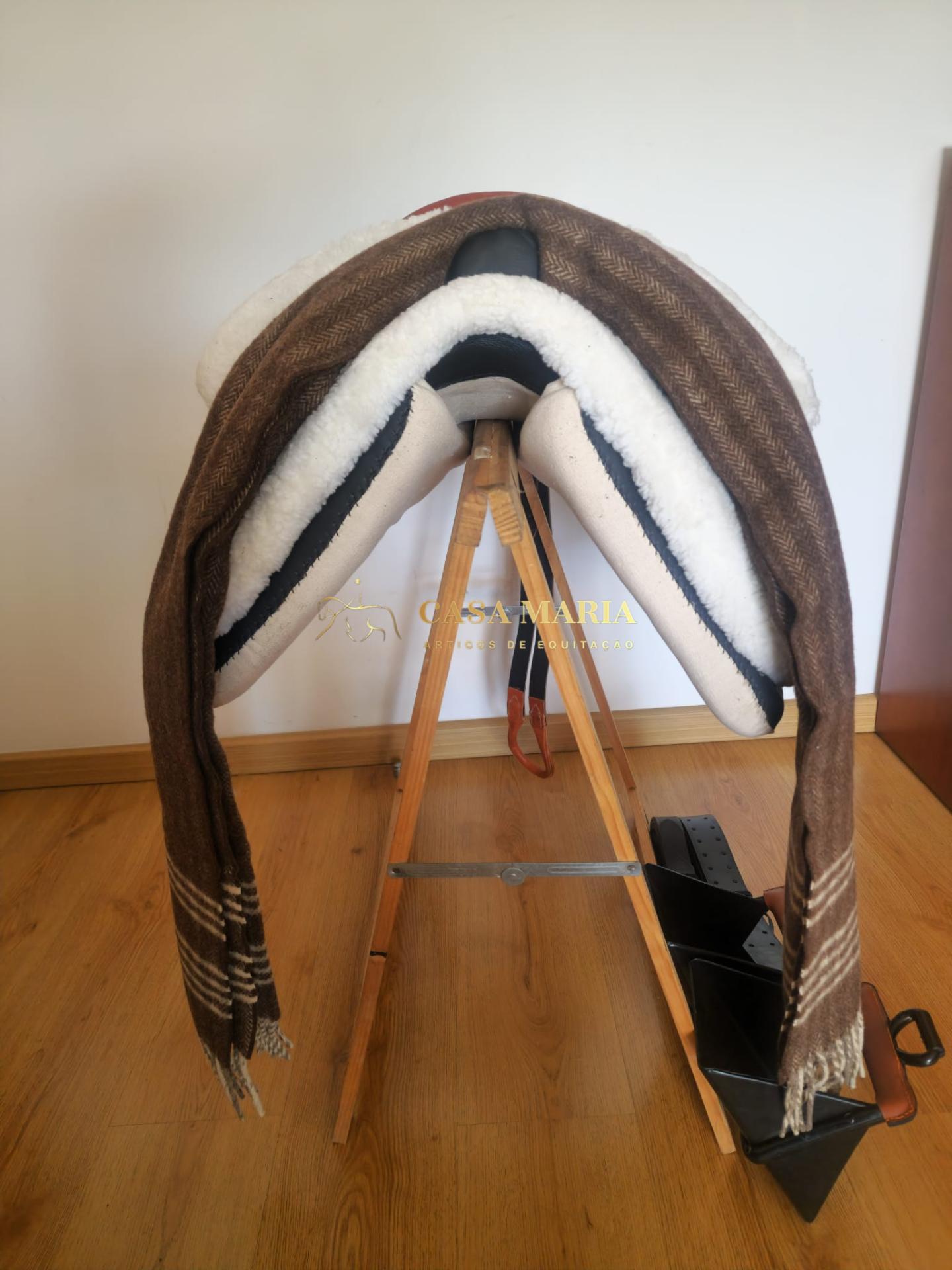 Sela de passeio com acolchoado branco e tecido castanho às riscas em suporte de madeira