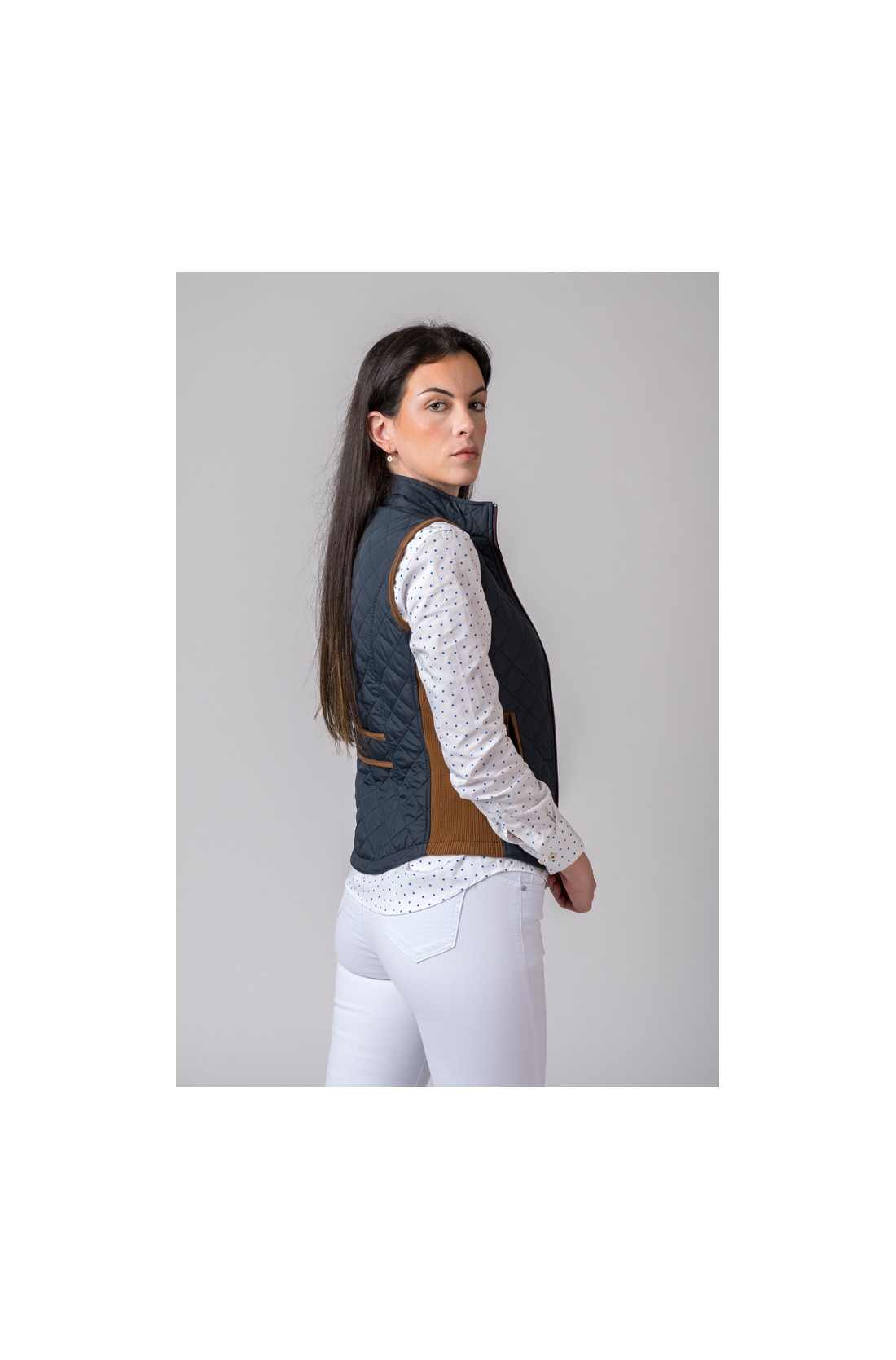 Colete feminino acolchoado azul escuro com painéis castanhos e camisa branca com pontos azuis