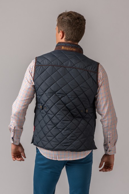 Homem visto de costas com colete matelassado azul escuro e camisa xadrez clara