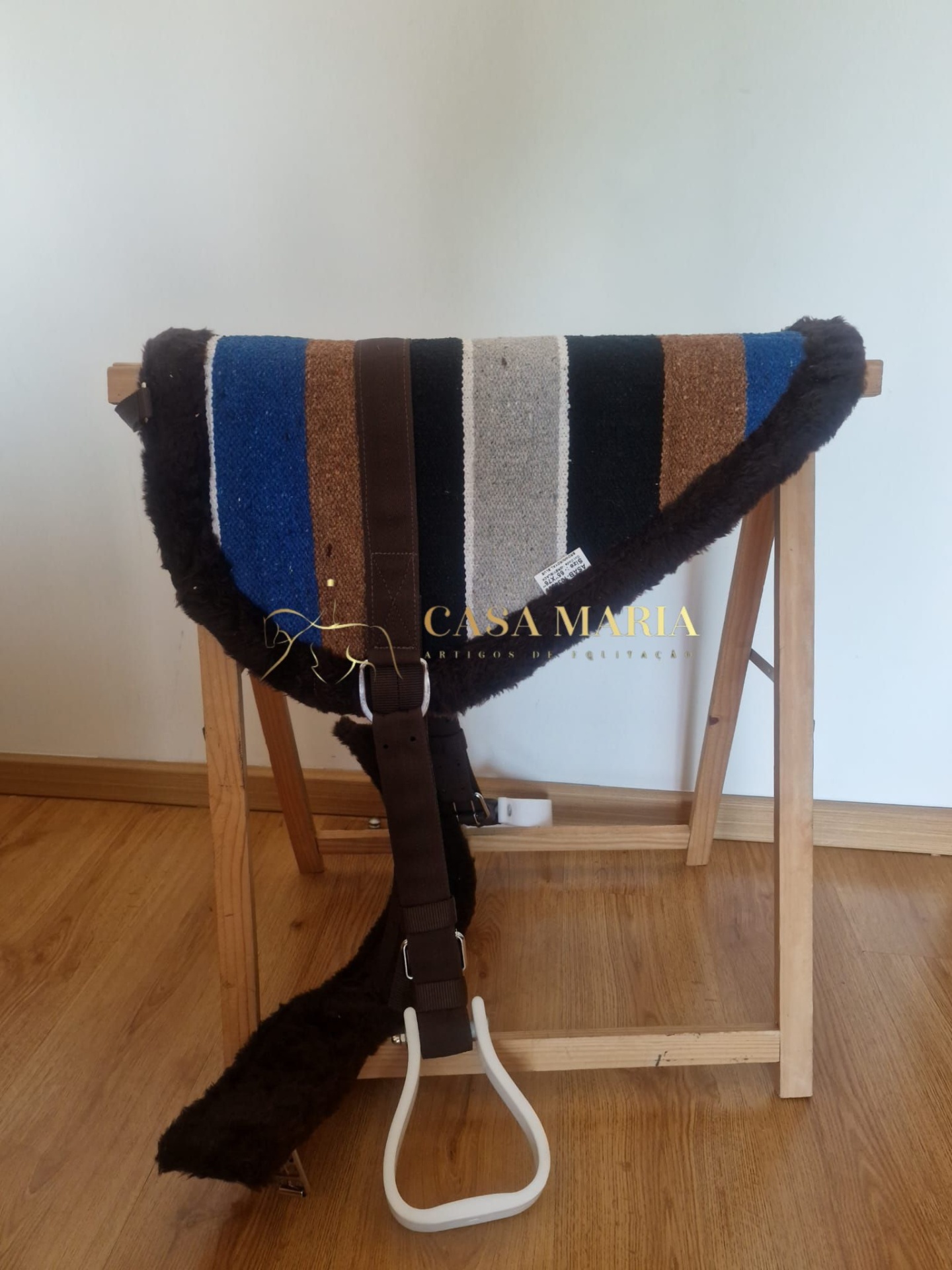 Alforge para cavalo com riscas coloridas e bordas de pêlo pendurado numa estrutura de madeira