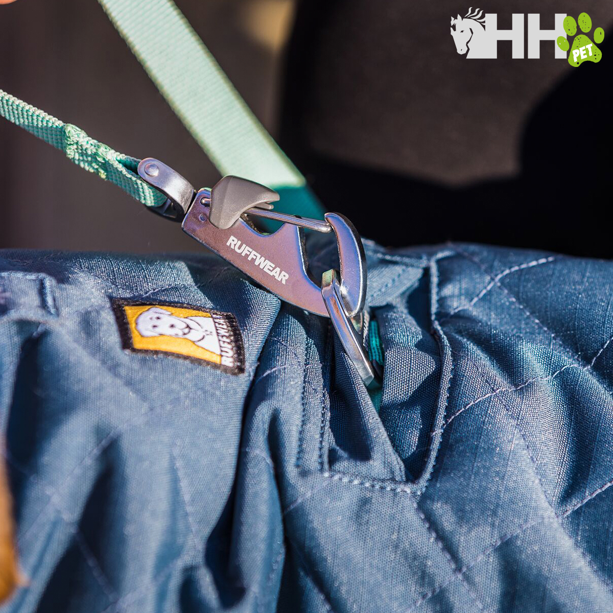 Clipe metálico prateado em corda verde preso a tecido azul acolchoado com etiqueta