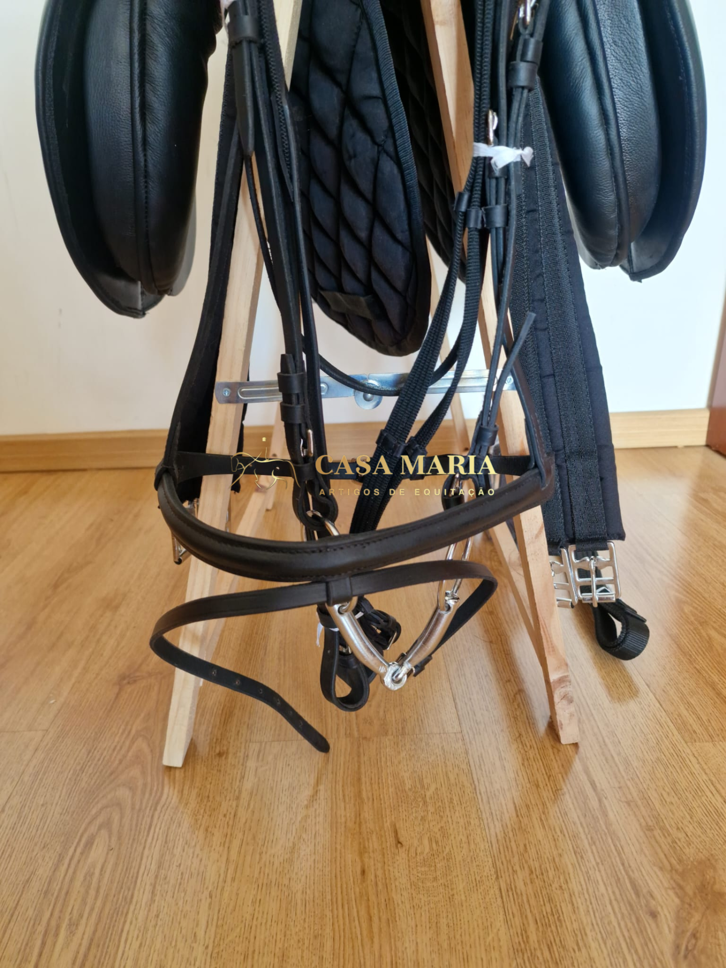 Conjunto de equipamentos e acessórios para equitação em suporte de madeira