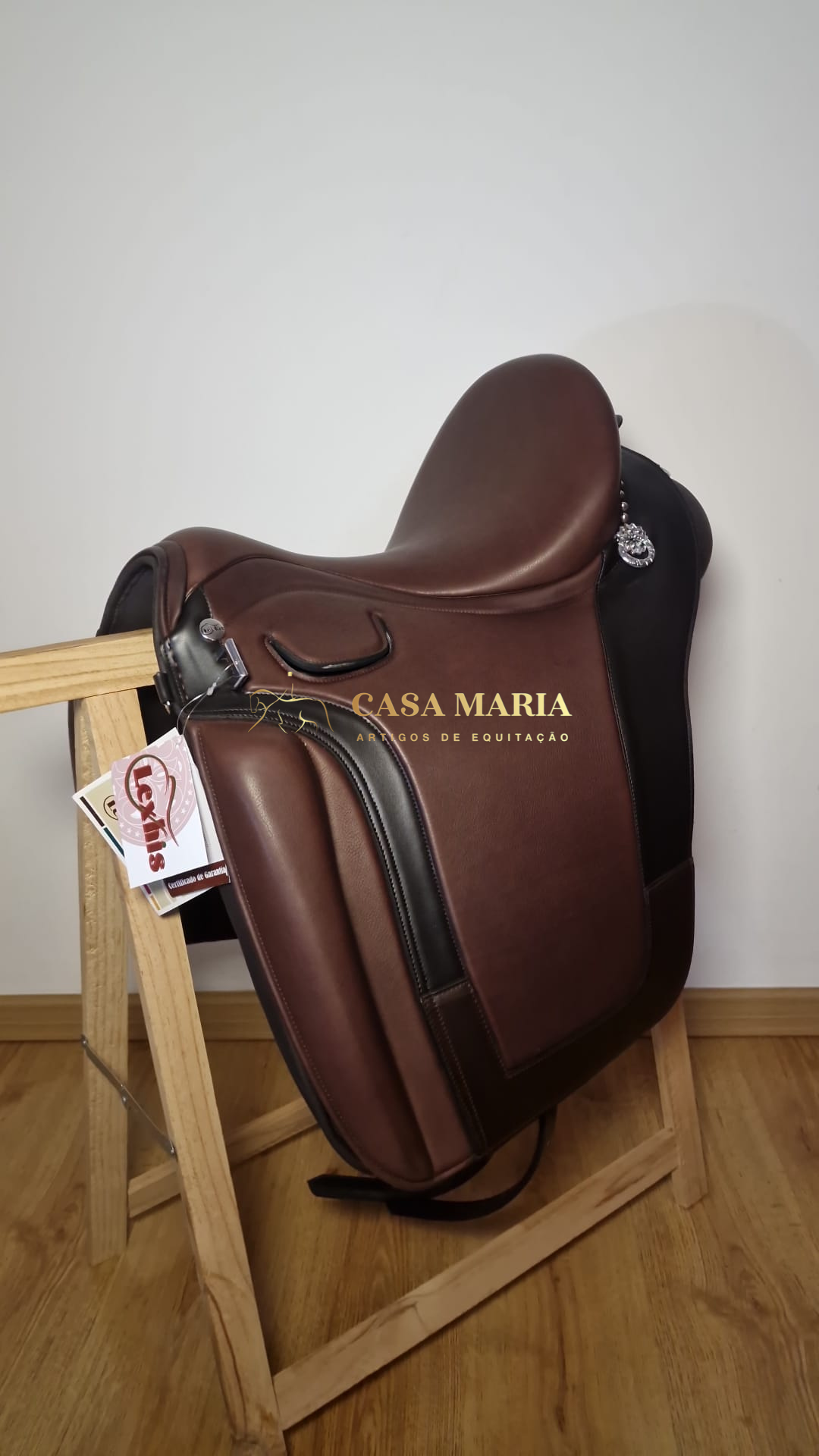 Sela de equitação em couro castanho com detalhes em preto sobre suporte de madeira