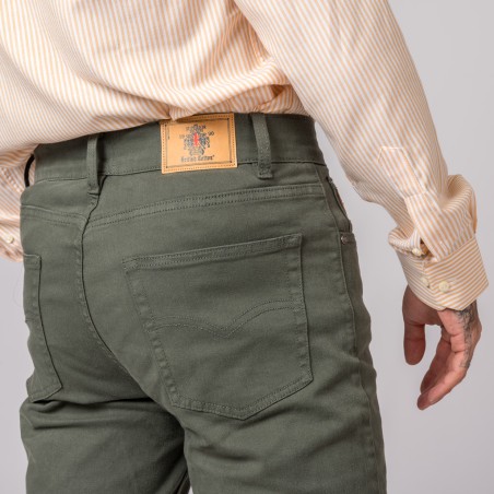 Calças verdes com etiqueta de couro e camisa riscada branca e bege.