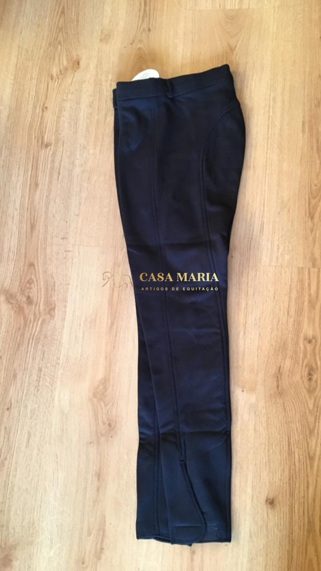 Calças pretas dobradas sobre piso de madeira