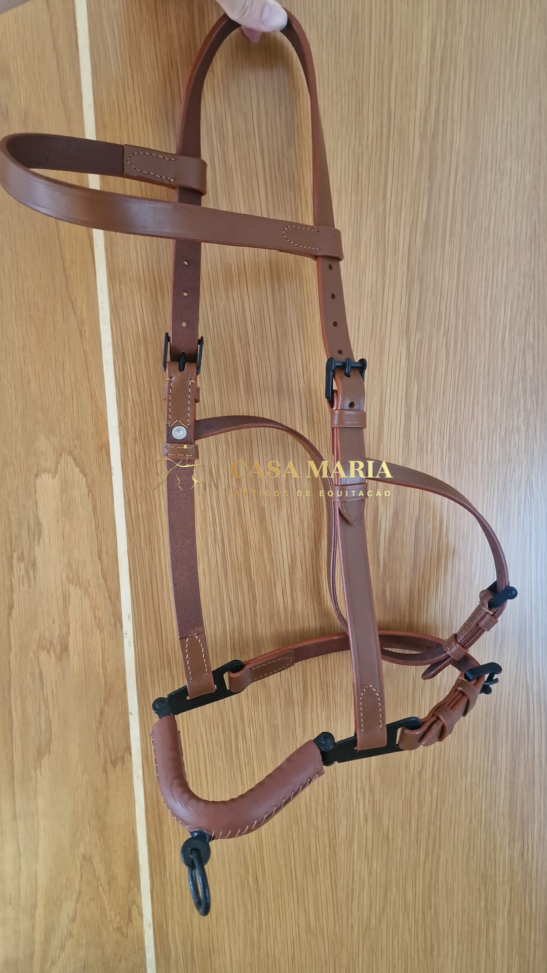 Cabresto de couro castanho pendurado numa superfície de madeira clara