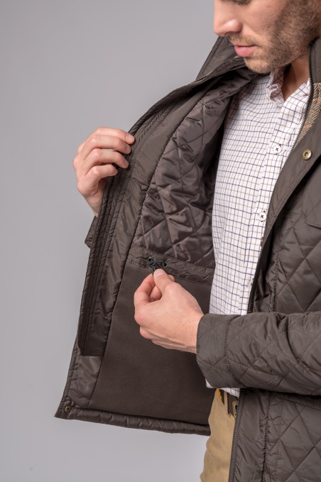 Casaco matelassé castanho aberto mostrando interior com padrão de losangos, camisa branca aos quadrados, fundo cinzento