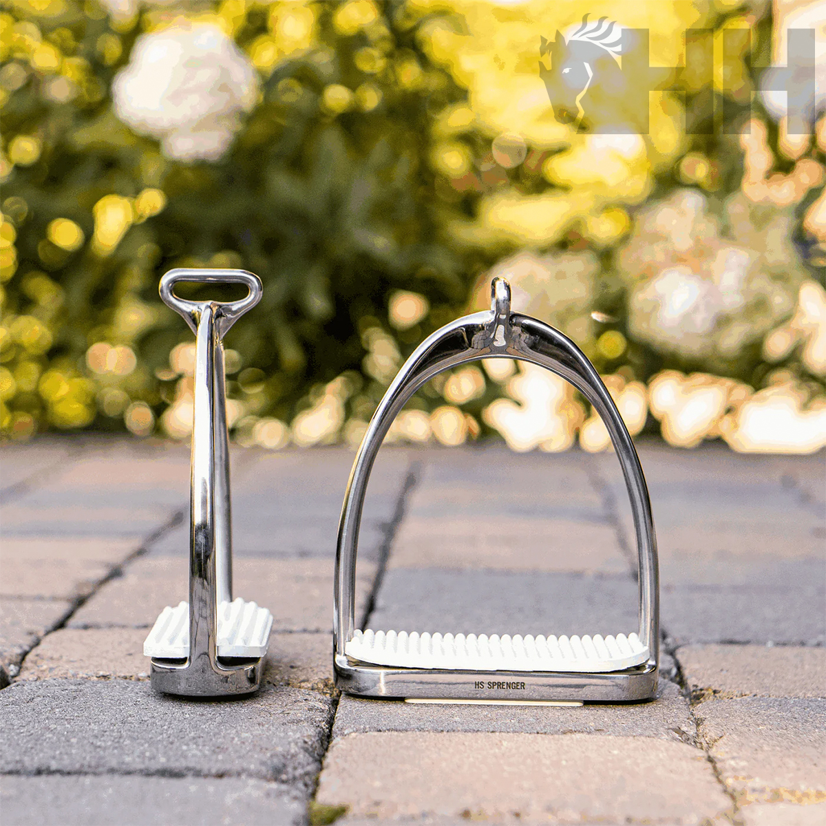 dois estribos metálicos prateados com superfícies brancas antiderrapantes em piso de pedra