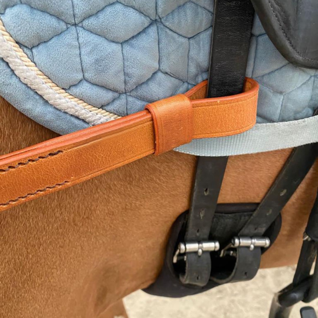 Trabalho aproximado de sela de cavalo com cinto alaranjado e manta azul clara