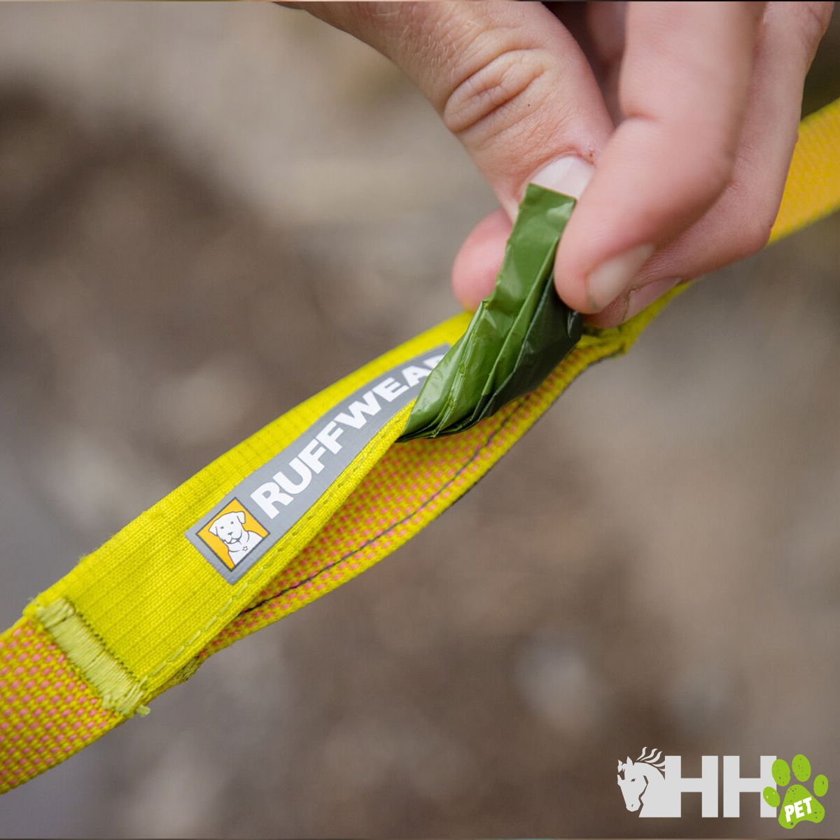 Correia amarela para cão com etiqueta RUFFWEAR e mão a colocar folha verde