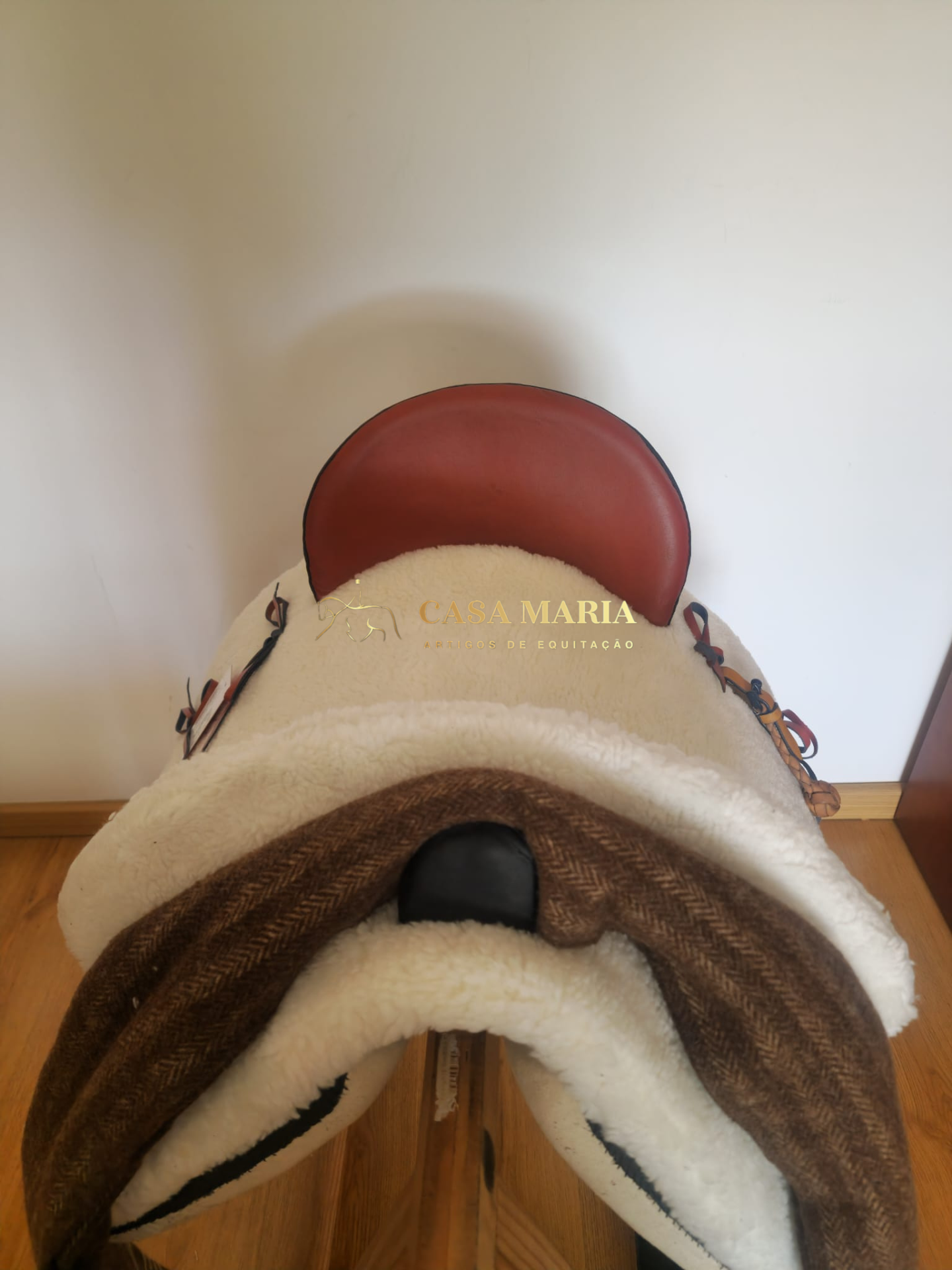 Sela de equitação em couro e tecido peludo com texto 'CASA MARIA ARTE DE EQUITAÇÃO'