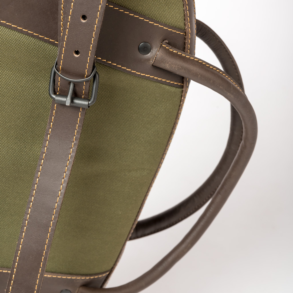 Detalhe de mala verde oliva com pele castanha e alça