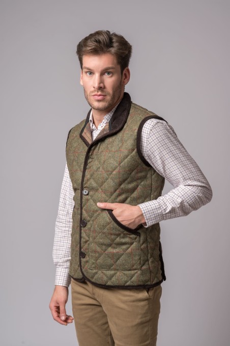 Homem a usar colete acolchoado verde e camisa branca de quadrados pequenos