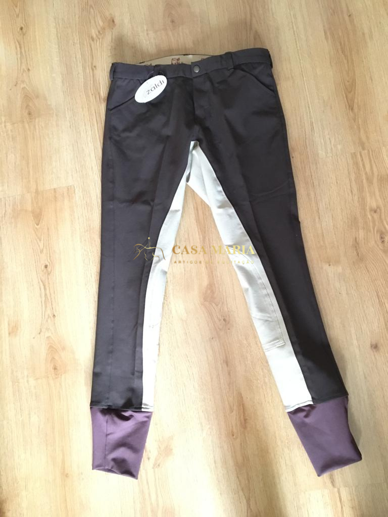 Calças de equitação castanho escuro com painéis brancos e punhos roxos em chão de madeira