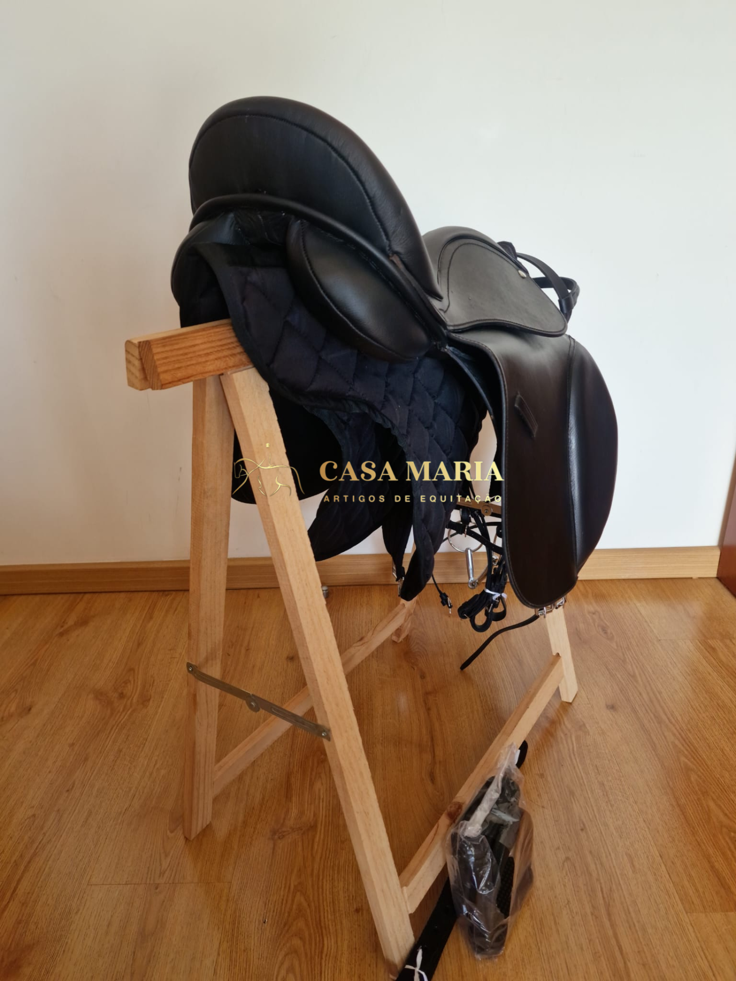 Sela de equitação preta em couro numa estrutura de madeira