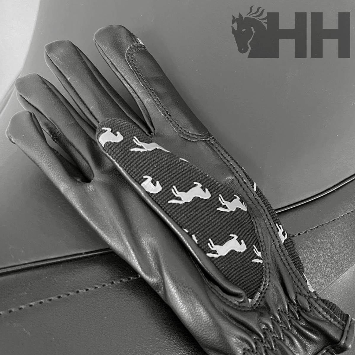 Luvas pretas em couro com padrão branco de cavalos e detalhes acolchoados