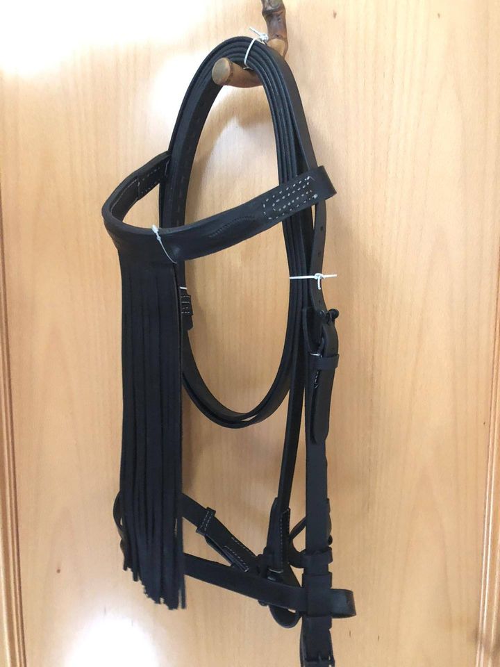 Bridão preto de pele com franjas suspenso num cabide