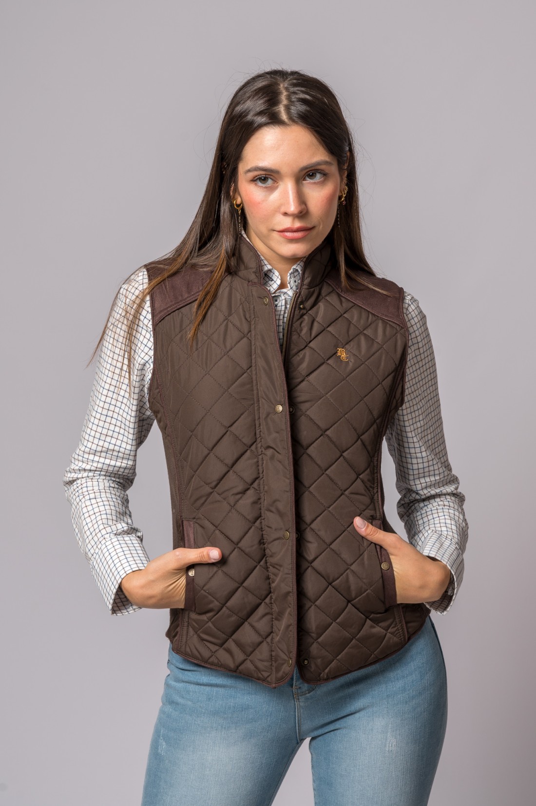 Colete matelassé castanho feminino com camisa xadrez e jeans azuis